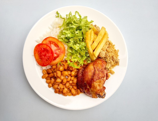 Un plato de comida con frijoles, frijoles y un tomate.