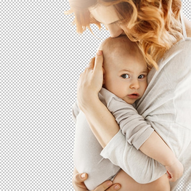 Portrait d'un doux petit enfant qui regarde la caméra avec une expression d'intérêt tandis que sa mère se serre tendrement dans ses bras et embrasse son nouveau-né.