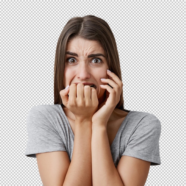 Portrait d'une jeune femme blanche malheureuse et belle avec de longs cheveux noirs dans un t-shirt gris décontracté rongeant les doigts avec une expression effrayée