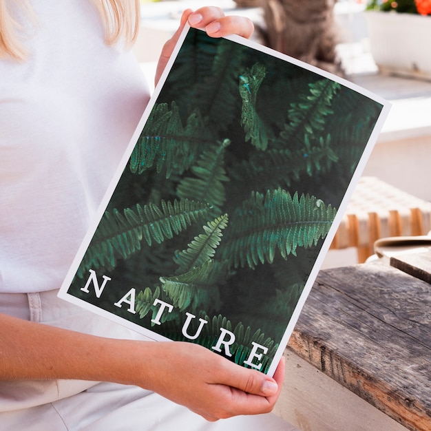 Primer plano de las manos mostrando una revista de naturaleza simulacro