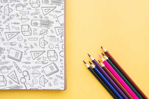 Retour à la maquette de l'école avec une couverture de cahier et des crayons