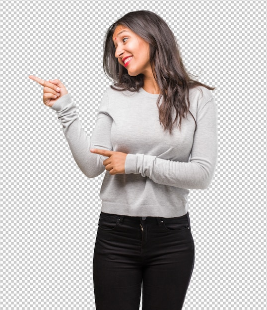 Retrato de joven india apuntando hacia un lado, sonriendo sorprendido presentando algo, natural y casual