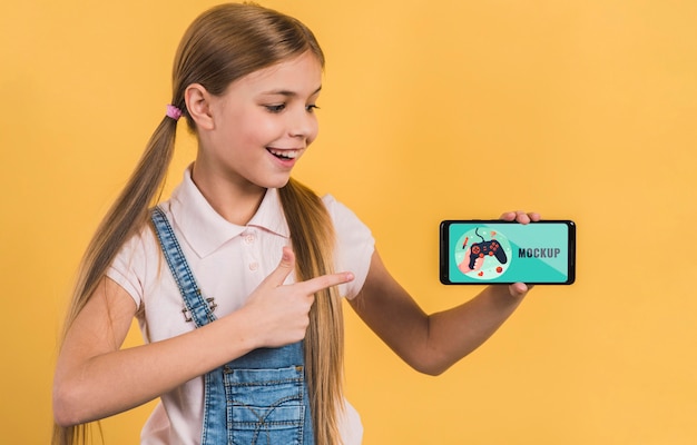 Retrato de niña sosteniendo teléfono móvil con maqueta