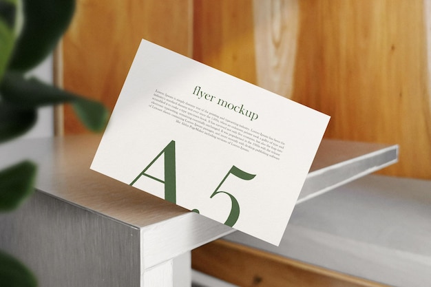 Sauberes minimales A5-Flyer-Mockup auf dem oberen Tischhintergrund mit Blättern PSD-Datei