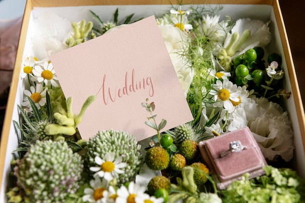 Schachtel gefüllt mit verschiedenen Blumen und einem Ehering
