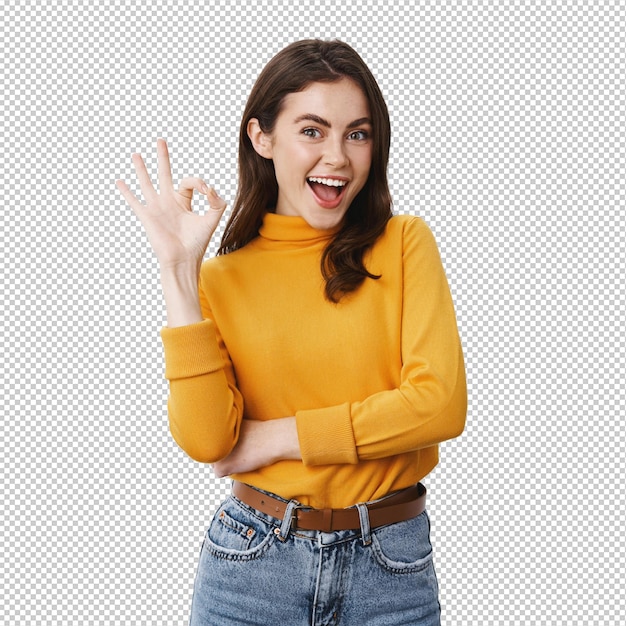 Sehr gut lächelndes junges weibliches Model mit natürlichem Make-up zeigt okay Zeichen und sagt ja bestätigen Produkt ist in Ordnung genehmigen und wie etwas steht auf weißem Hintergrund
