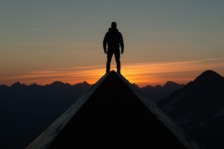 PSD silhouette mann steht auf einem berggipfel bei sonnenuntergang mit blick auf eine riesige bergkette