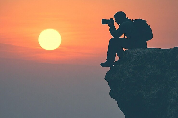 PSD silhouette of photographer taking sunset photos from a clifftop