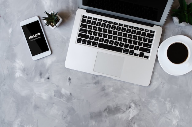 Smartphone blanco con pantalla en blanco negro en escritorio de oficina con laptop y taza de café