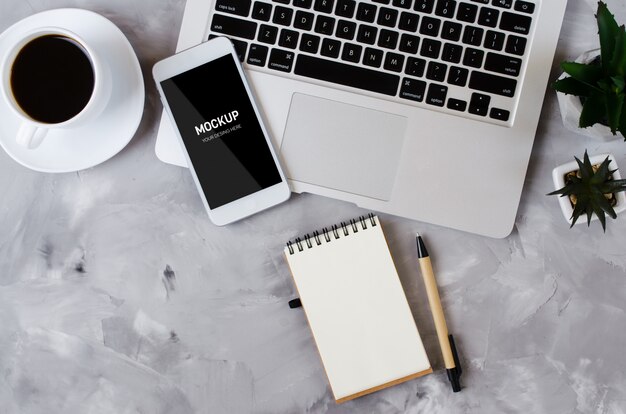 PSD smartphone blanco con pantalla en blanco negro en escritorio de oficina con laptop y taza de café