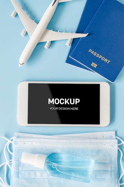 Smartphone mit Flugzeugmodell, Reisepass, Gesichtsmaske und Desinfektionsmittel