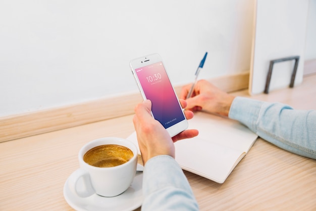 Smartphone-Modell mit Kaffee auf dem Schreibtisch