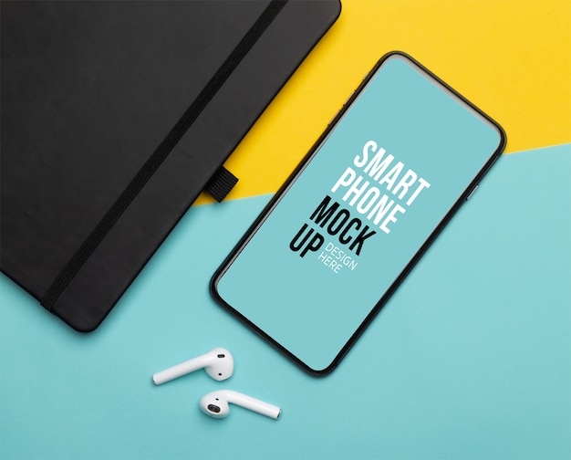 Smartphone preto com tela e fones de ouvido sem fio e notebook