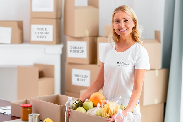 Sorridente voluntária segurando uma caixa de doação com comida