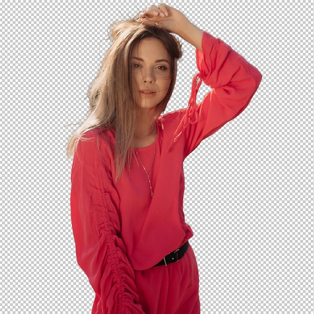 Stylisches Model mit fliegendem dunkelhaarigen, rosa Sommerkleid sieht in die Kamera und berührt ihre Haare auf dem Hintergrund eines sandigen Strandes in der Sonne