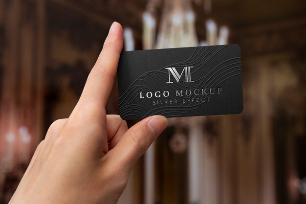 Tarjeta de visita en la mano con el logotipo de plata