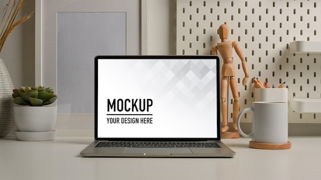 Tavolo da lavoro con mockup di laptop e decorazioni nella stanza dell'ufficio domestico
