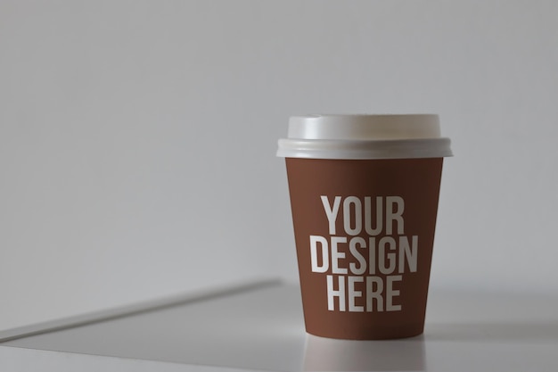 Tazza da caffè in carta marrone sul tavolo mockup design personalizzato colore mutevole primo piano