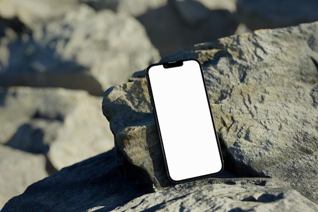 Telefon 13 Pro auf einem Felsen mit einem leeren Bildschirm Smartphone-Modell für Design-Branding