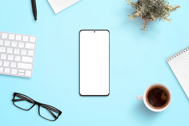 Telefon auf blauem Schreibtisch, umgeben von Büromaterial. Saubere, flache Komposition für reaktionsschnelle Designwerbung für Apps oder Webseiten