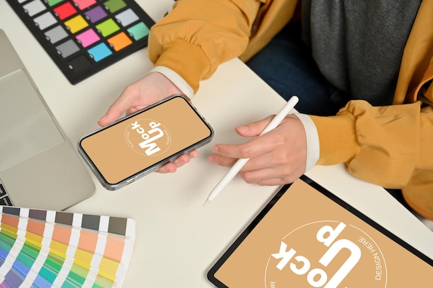 Toma recortada de manos de diseñador femenino trabajando con smartphone