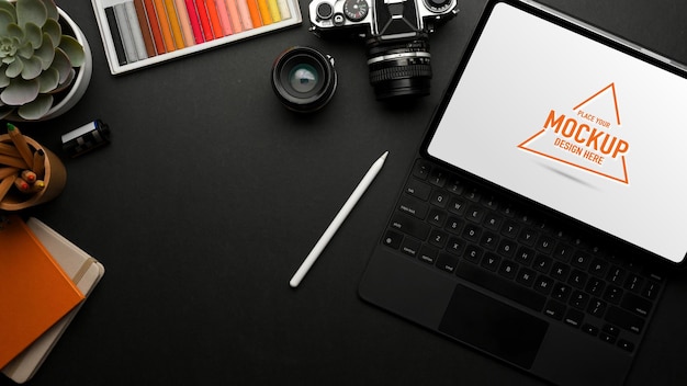 Top view of dark workspace with digital tablet camera paint tools stationery