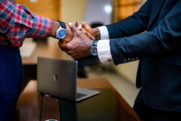 Two men shake hands over a laptop cutout png