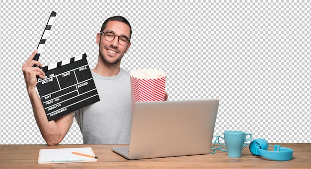 Überraschter junger mann, der einen film auf seinem laptop aufpasst und popcorn isst