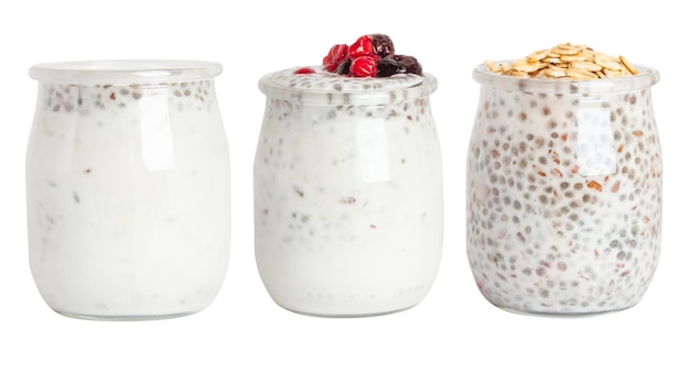 Um conjunto de frascos de iogurte com sementes de chia, granola e bagas em um frasco de vidro em um fundo em branco.
