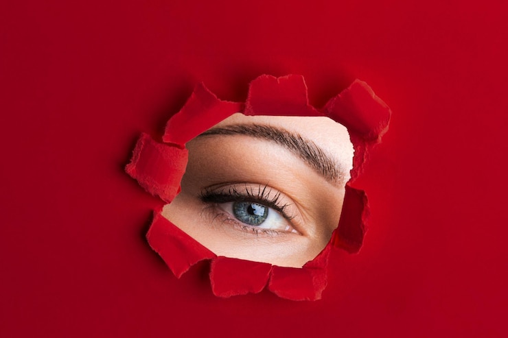 PSD um olho de mulher olha para fora de papel vermelho rasgado