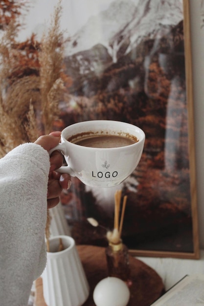 uma pessoa segurando uma xícara de café com o logotipo nele