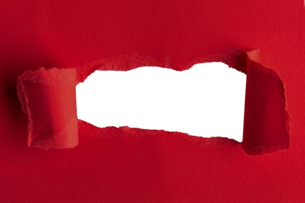Una carta rossa spessa strappata al centro con un buco vuoto e uno sfondo vuoto dietro.