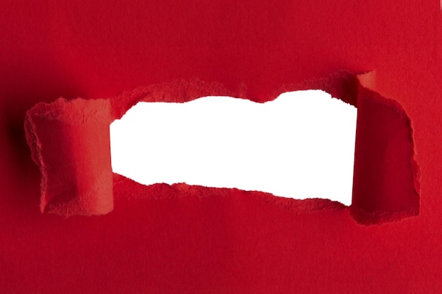 Una carta rossa spessa strappata al centro con un buco vuoto e uno sfondo vuoto dietro.