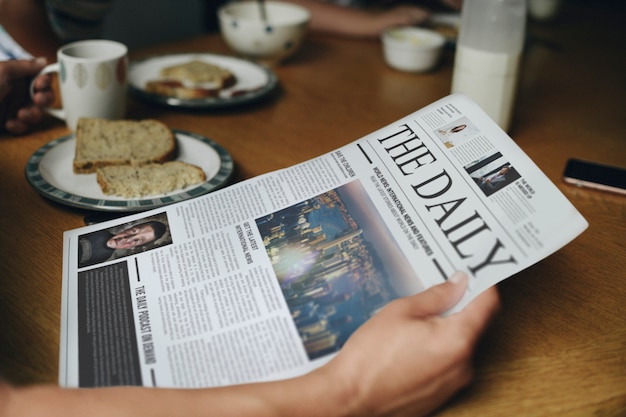 Uomo che legge le notizie al tavolo della colazione