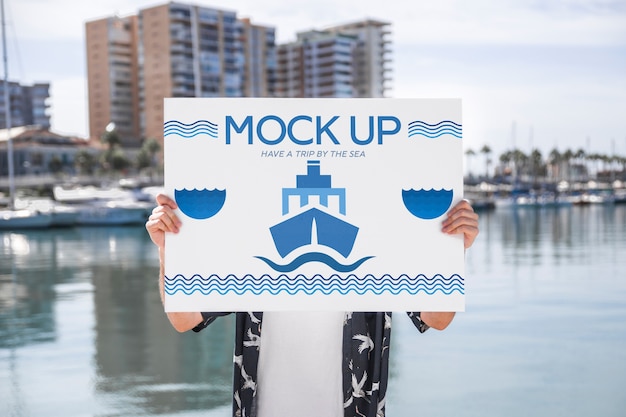 Uomo che presenta poster mockup di fronte all&#39;acqua