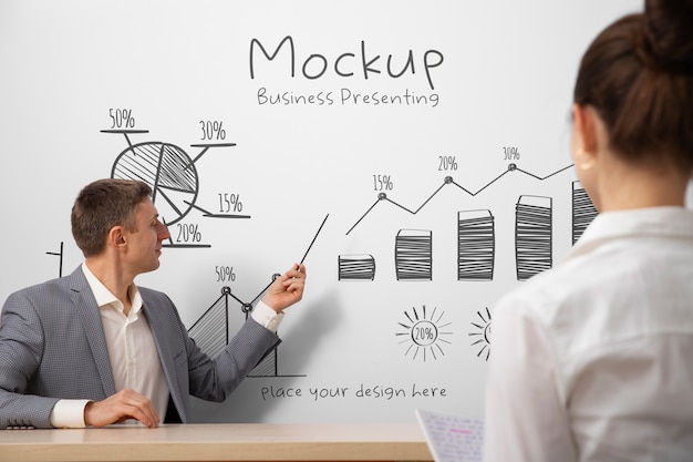 Uomo d'affari che presenta in una riunione su un grande mockup di lavagna bianca