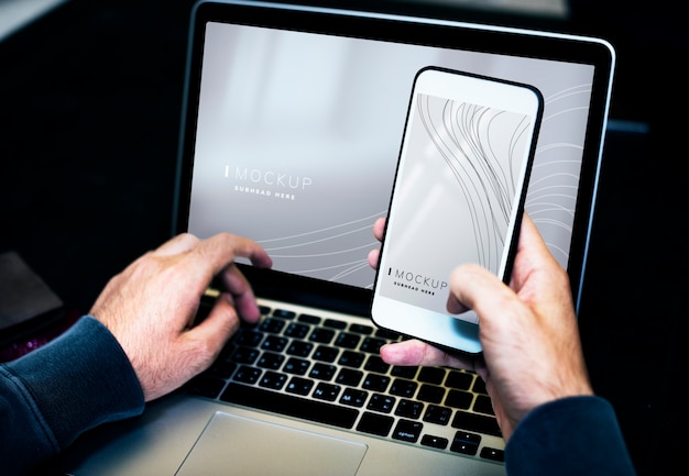 Uomo d&#39;affari utilizzando un computer portatile e un modello di telefono cellulare