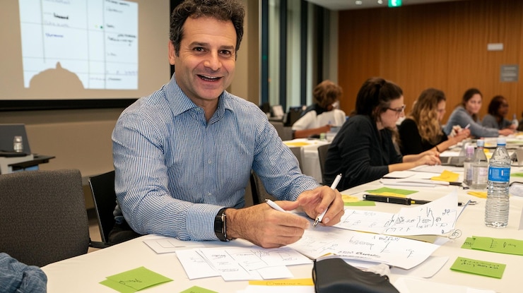PSD uomo sorridente seduto a un tavolo durante un workshop che partecipa attivamente e si impegna con i colleghi