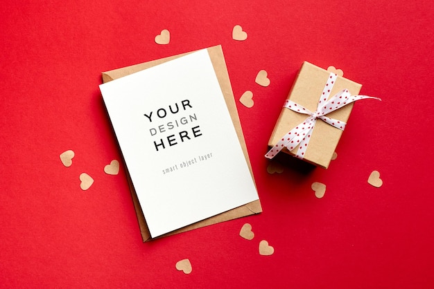 Valentinstagskartenmodell mit Geschenkbox und kleinen Papierherzen auf Rot