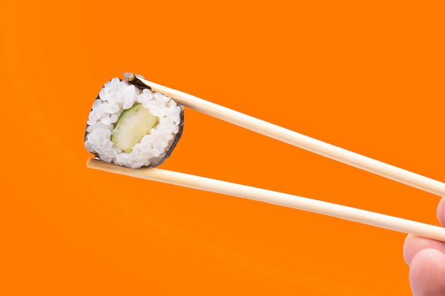 veganes Sushi aus Gurken, Reis und Algen, das einfach mit Stäbchen gehalten und isoliert wird