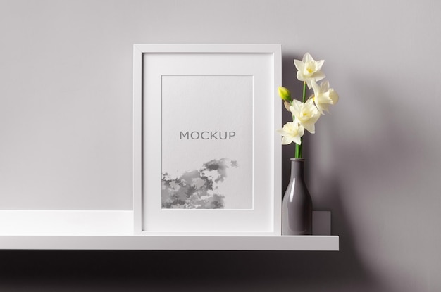 Vertikales weißes kunstwerkrahmenmodell auf regal mit frühlingsnarzissenblumen
