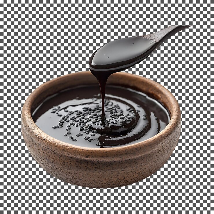 PSD se vierte con cuchara el caramelo de sésamo negro en un cuenco aislado sobre un fondo transparente