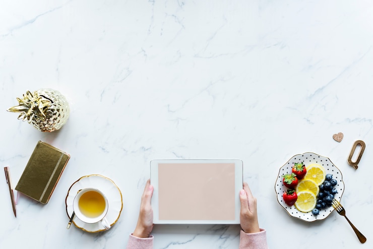 PSD vista aérea de mujer usando una tableta digital en una mesa de mármol con espacio de diseño