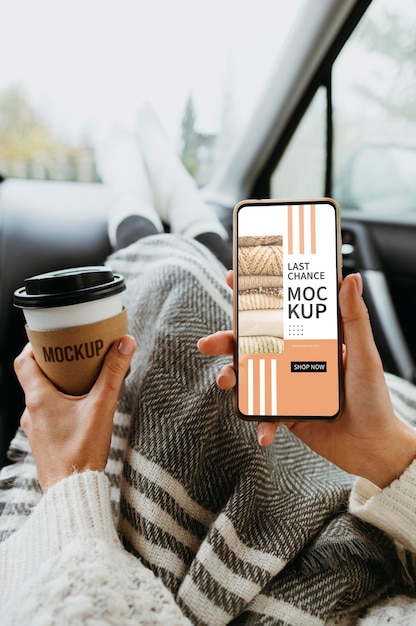 Vista dall'alto a portata di mano con mockup di smartphone e tazza di caffè