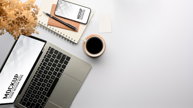 Vista dall'alto del tavolo da lavoro con mockup di laptop e smartphone