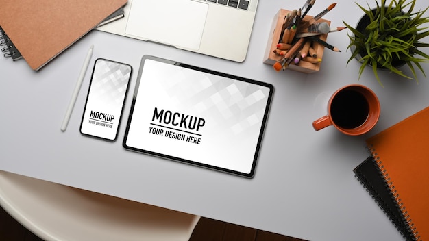 Vista dall'alto del tavolo da lavoro con mockup di tablet e smartphone