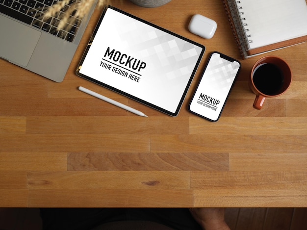 Vista dall'alto del tavolo da lavoro in legno con mockup di tablet e smartphone