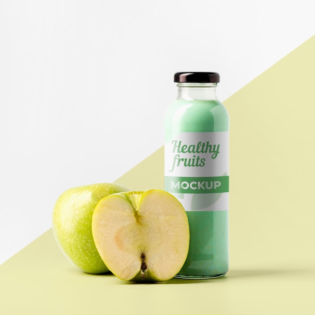 Vista frontal de la botella de jugo transparente con manzanas