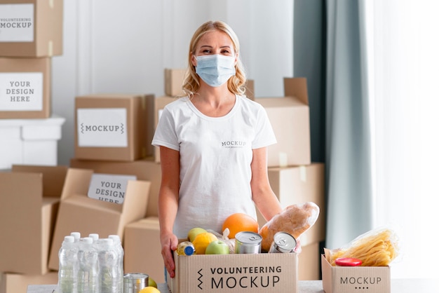 Vista frontal de voluntária com máscara médica preparando doações de alimentos