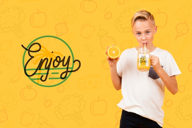 Vista frontal del niño bebiendo jugo de naranja